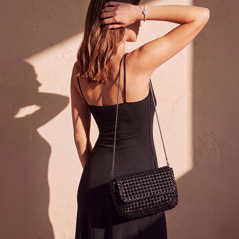 Model in a tailored blazer carrying a chain-strap leather tote
